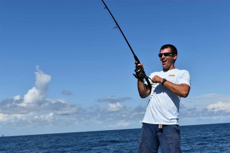 Captain Drew Bateman aboard the 42-foot catamaran reeling in a big fish while in the Gulf of Mexico