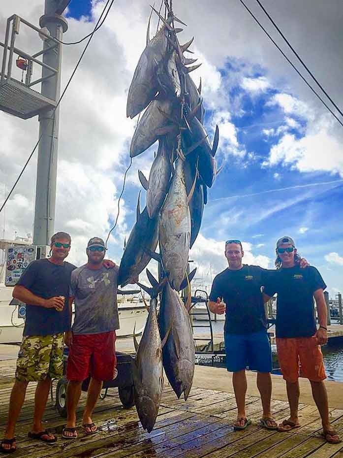 Captain Drew Bateman and charter guests at Cypress Cove Marina posing with the multiple massive yellowfin tuna caught in one day on a charter fishing trip in the gulf of mexico with Paradise Outfitters