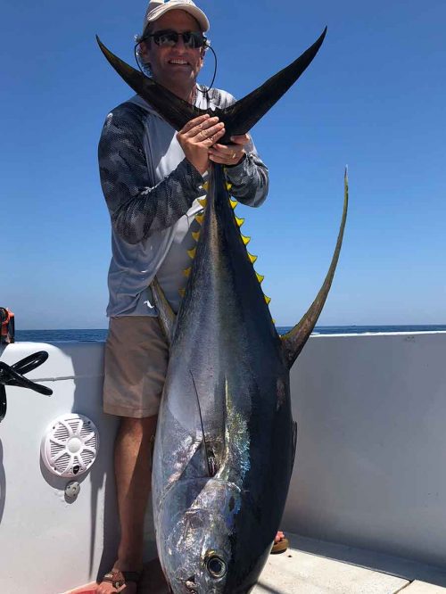 man holding yellowfin tuna on paradise outfitters charter boat in the gulf of mexico